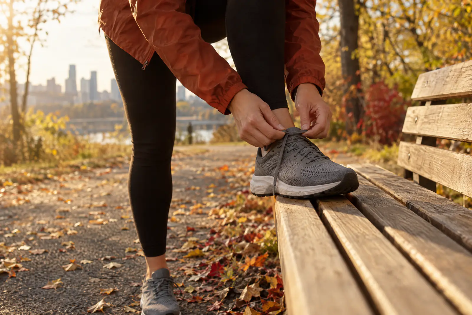 A runner lacing a running shoe on a park bench